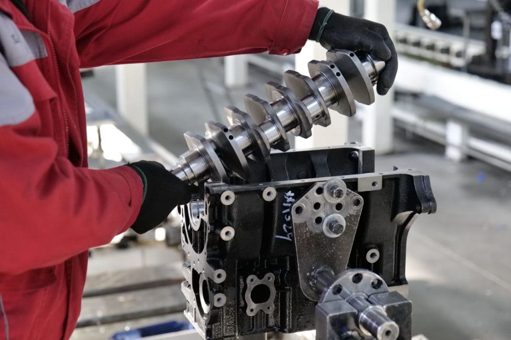 Work Mechanic working on a crankshaft installation in an engine block in an industrial setting.