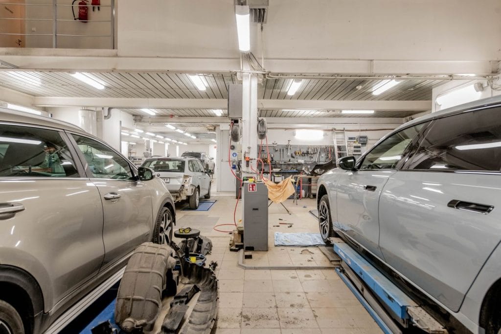 Work Interior of an automotive repair shop with cars undergoing maintenance and servicing.