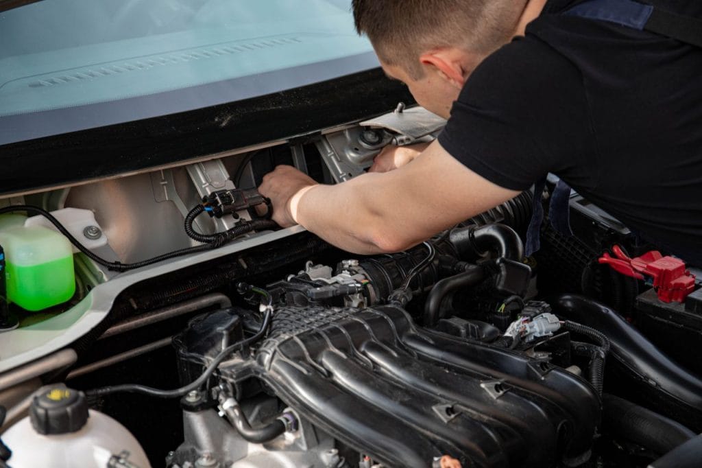 Work Mechanic fixing a car engine under the hood showing detailed components.